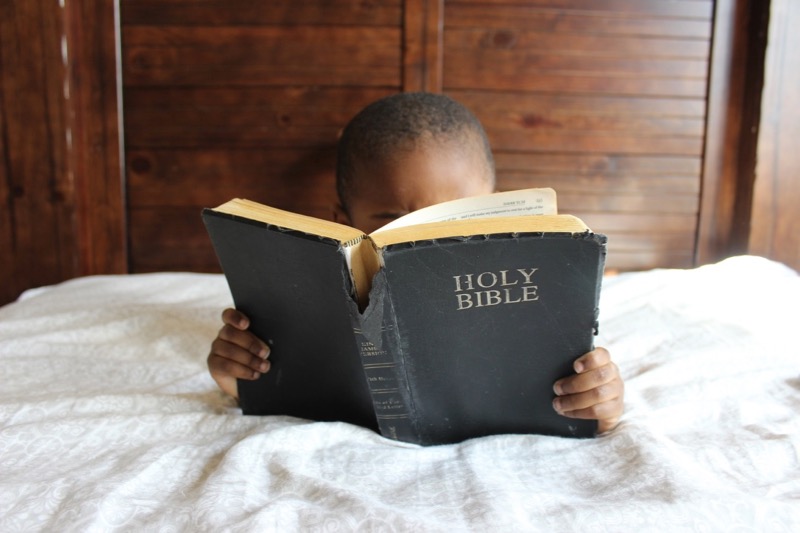 Kind liest in der Bibel